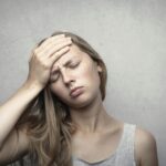A woman in distress holding her head, expressing emotion and fatigue.